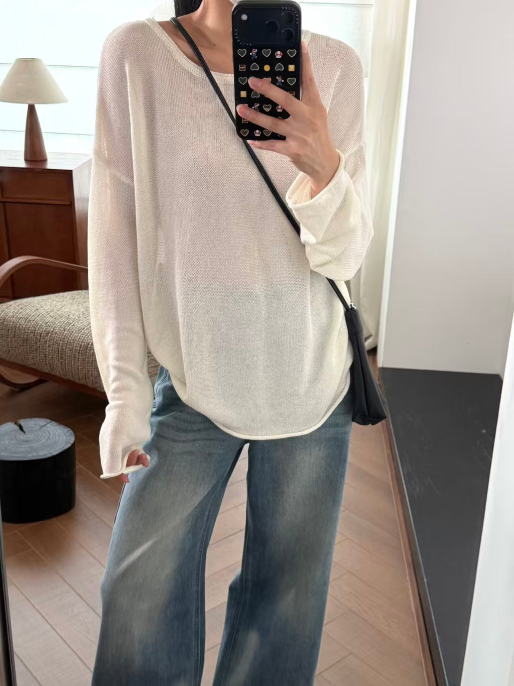 Off-white sheer knit top with wide-leg blue jeans, mirror shot