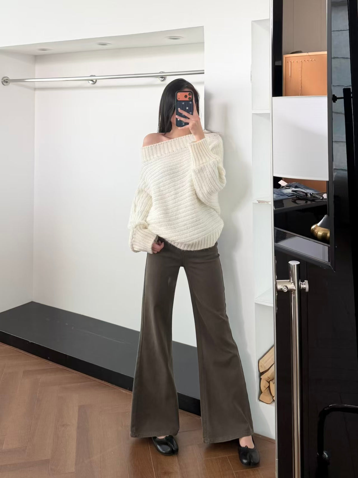 Cream off-shoulder chunky knit sweater mirror shot front, styled with grey wide-leg trousers